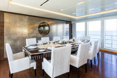 An elegant dining room aboard a yacht features a beautifully set table with a stunning wall art piece.