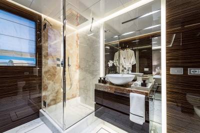 Luxurious marble and rich wood create a serene spa-like atmosphere in this opulent yacht bathroom.