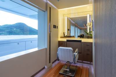 A luxurious salon chair sits before a vanity mirror, overlooking a serene ocean view from a yacht.