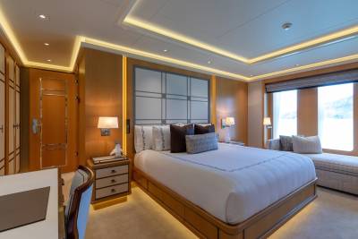 Luxurious wood-paneled bedroom features a plush bed, elegant lighting, and a serene view through the large windows.