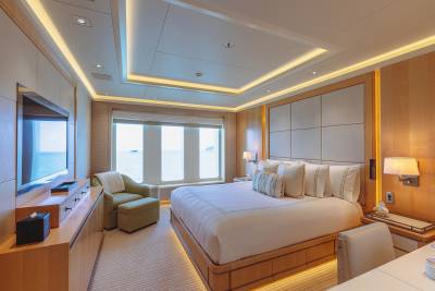Luxurious yacht stateroom offers a serene retreat with ocean views and elegant wood finishes.