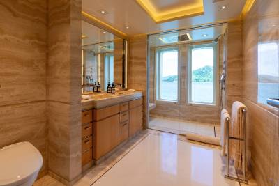 Luxurious yacht bathroom features marble walls, a sleek vanity, and a glass-enclosed shower with stunning ocean views.