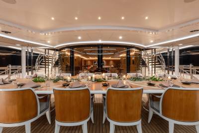 A beautifully set dining table on a yacht awaits guests with elegant place settings and floral arrangements.