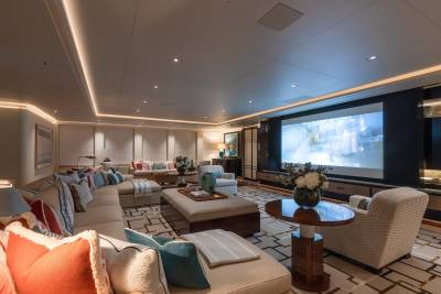 This luxurious yacht lounge offers a cinematic experience with a large projector screen and plush seating.