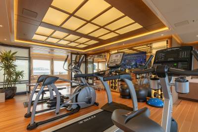 This luxurious yacht gym features state-of-the-art cardio equipment and a stunning city view on the screen.