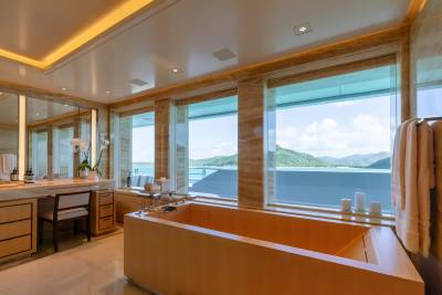 This luxurious bathroom offers a stunning view of lush green islands and turquoise waters through expansive windows.
