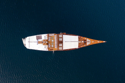 A traditional wooden schooner glides across the deep blue ocean, its decks inviting relaxation.