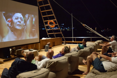 Guests enjoy an outdoor movie screening under the stars on a luxurious yacht deck.
