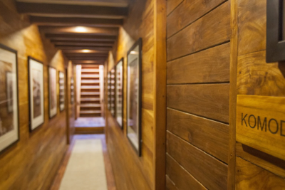 A wooden hallway, adorned with framed art and a sign reading "Komodo," leads towards a staircase.