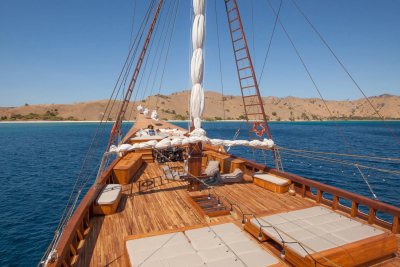 Relax on the sun-drenched deck of a traditional wooden schooner sailing through turquoise waters.