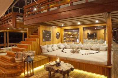 Relax on the plush daybed of this luxurious wooden deck, illuminated by soft lighting and the glow of candles.
