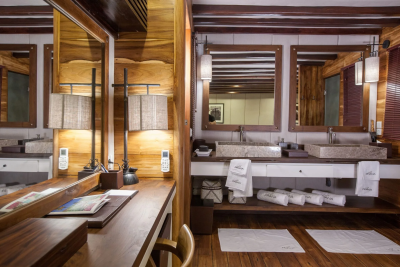 Luxurious wooden interiors and stone sinks create a serene spa-like atmosphere in this elegant bathroom.