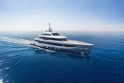 A sleek, modern yacht glides through the deep blue ocean under a clear sky.