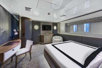 This luxurious yacht cabin features a sleek modern design with a comfortable bed, a stylish desk, and a large window offering ocean views.