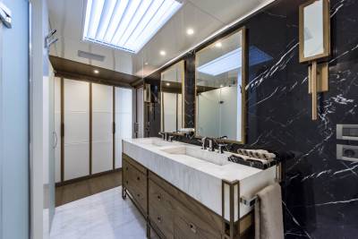 Luxurious yacht bathroom features a double vanity with marble countertops and a striking black marble accent wall.