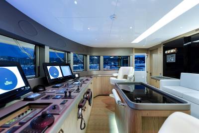 The modern yacht bridge offers panoramic views of a serene harbor at dusk, equipped with advanced navigation systems and comfortable seating.