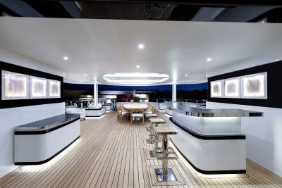 Elegant bar seating and a circular dining table create a sophisticated atmosphere on this yacht's deck.