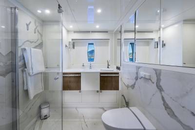 A luxurious yacht bathroom features marble accents, a sleek vanity, and a porthole with a stunning ocean view.