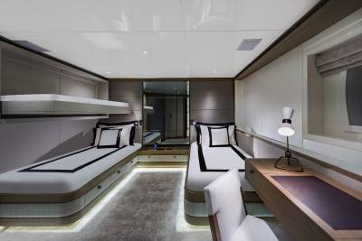 Luxurious twin beds with crisp white linens and black accents are perfectly arranged in this elegant yacht cabin.