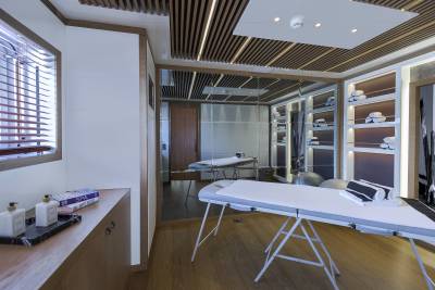 This luxurious spa room features massage tables, neatly folded towels, and a calming ambiance with wooden accents and soft lighting.
