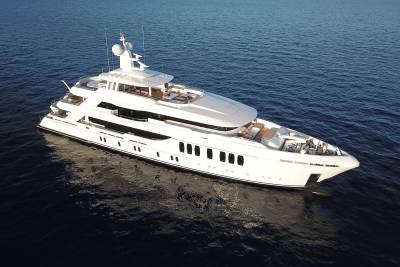 A luxurious white yacht glides serenely across the deep blue ocean under a clear sky.