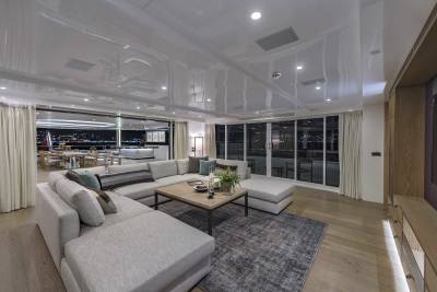 The luxurious yacht salon opens to a stunning night view of a city skyline and a beautifully set dining table on the deck.