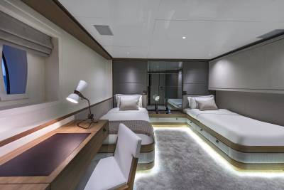 Luxurious twin beds with ambient lighting create a serene atmosphere in this elegant yacht cabin.