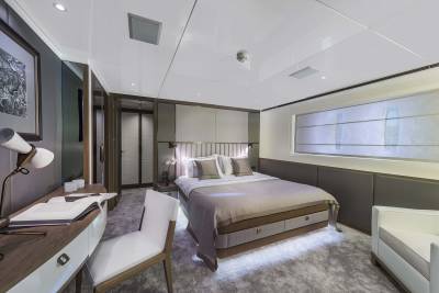 Luxurious yacht stateroom features a plush king-sized bed, elegant desk, and soft, ambient lighting.