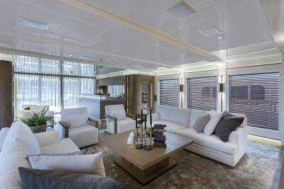 Luxurious white sofas and armchairs create a serene lounge area aboard a modern yacht.
