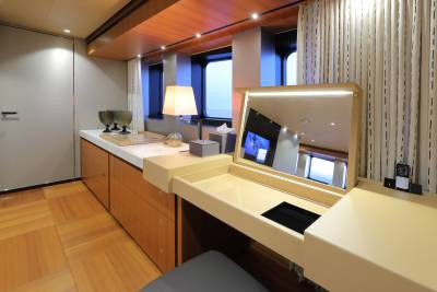 A vanity with a large illuminated mirror sits beside a window on a luxurious yacht.