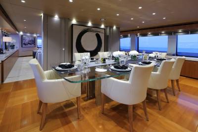 A luxurious dining room aboard a yacht offers a sophisticated setting for an elegant meal overlooking the ocean.