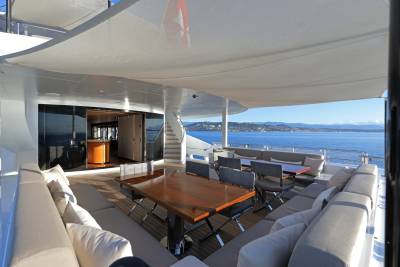 Luxurious yacht deck seating offers a stunning panoramic view of the Mediterranean coastline under a crisp blue sky.
