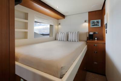 This luxurious yacht cabin offers a serene retreat with a comfortable bed, ample storage, and a picturesque view of the sea and mountains.