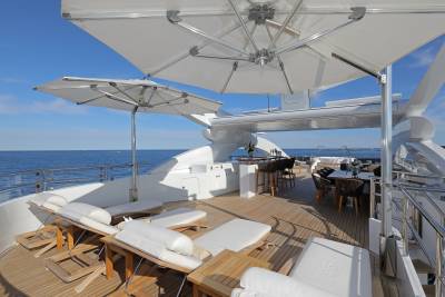 Luxurious sun loungers and a dining area await on the deck of this elegant yacht, offering a perfect spot to enjoy the azure sea.