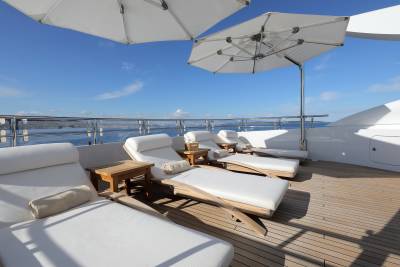 White lounge chairs and umbrellas offer a luxurious spot to relax on the deck of a yacht overlooking the blue ocean.