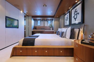 Luxurious yacht bedroom features a king-size bed, modern art, and a wall-mounted television for ultimate comfort at sea.