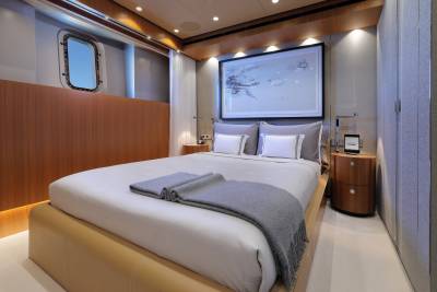 Luxurious yacht accommodations feature a plush bed, elegant artwork, and a porthole offering ocean views.