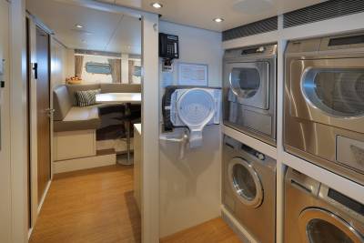 This yacht's laundry room features stacked Miele appliances and a cozy dining nook with ocean views.