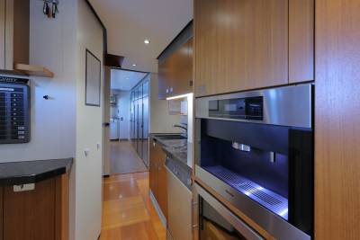 A sleek, modern galley features a built-in coffee machine and ample wooden cabinetry, perfect for preparing meals on board.