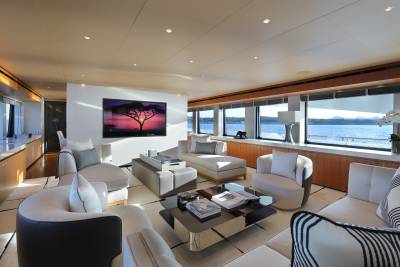 Sunlight streams into a luxurious yacht lounge, highlighting the elegant seating and expansive ocean views.