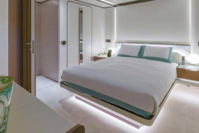 A modern bedroom features a floating bed with ambient under-lighting and a sleek bedside table.