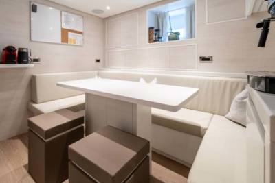 A modern dining nook with a white table and plush seating offers a cozy spot for meals aboard a luxurious yacht.