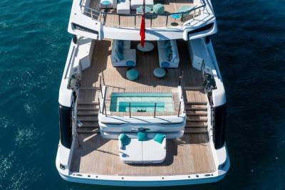 A luxurious yacht with a pool and lounge areas floats serenely on the deep blue ocean.