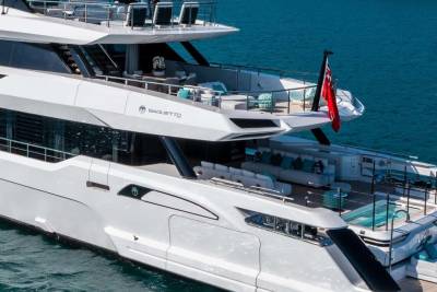 A luxurious white yacht with multiple decks and comfortable seating areas floats on the clear blue ocean.