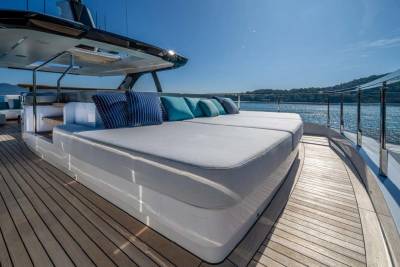 Luxurious sun loungers with plush cushions beckon relaxation on this elegant yacht's deck overlooking the sparkling sea.