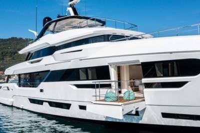A luxurious white yacht floats on calm blue waters, its open doors revealing an elegant interior.