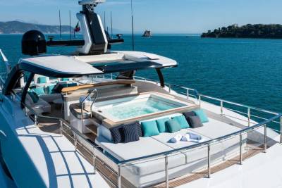 A luxurious yacht deck features a bubbling hot tub and plush seating, perfect for enjoying the serene ocean views.