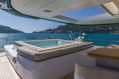 Relax in the jacuzzi on the deck of this luxurious yacht, surrounded by stunning coastal scenery.