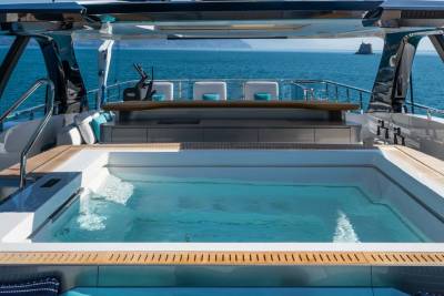 A luxurious yacht features a serene hot tub with crystal-clear water, overlooking a tranquil sea.