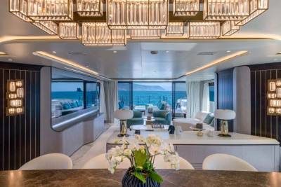 A luxurious yacht interior features a stunning crystal chandelier and panoramic ocean views.